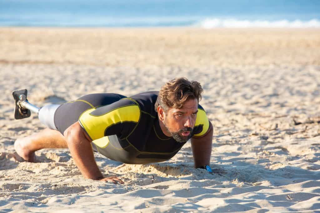 sporty disabled man pushing up on beach